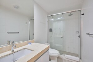 A bathroom with a sink, mirror, toilet, and glass-enclosed shower. - Pardo 510 Suites By Geko (Miraflores)