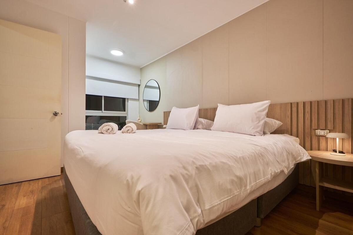 Una habitación de hotel moderna con una cama grande, una mesita de noche con lámpara y un espejo en la pared.