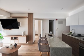 A modern kitchen with a central island, built-in appliances, and a flat-screen TV mounted on the wall. - Stylish Inclán 343 Apartment By Geko (Lima)