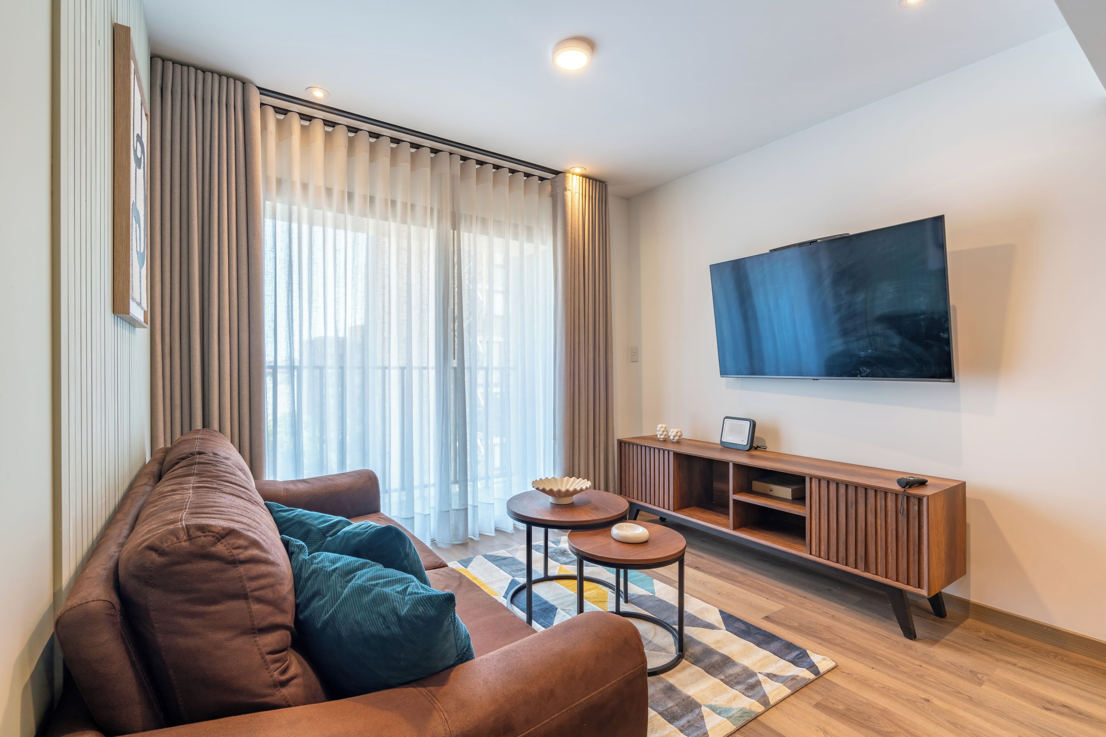 A modern living room with a sofa, a coffee table, and a TV mounted on the wall.