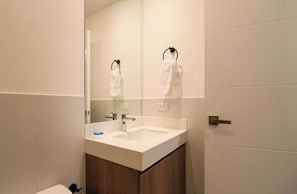 Ein modernes Badezimmer mit einem weißen Waschbecken, einem Spiegel und einem Handtuchhalter.