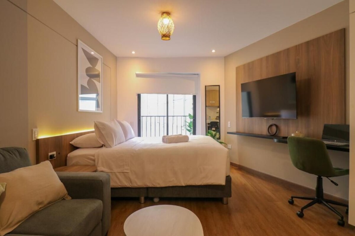 Ein modernes Schlafzimmer mit einem Bett, einem Schreibtisch, einem Stuhl und einem Fernseher.
