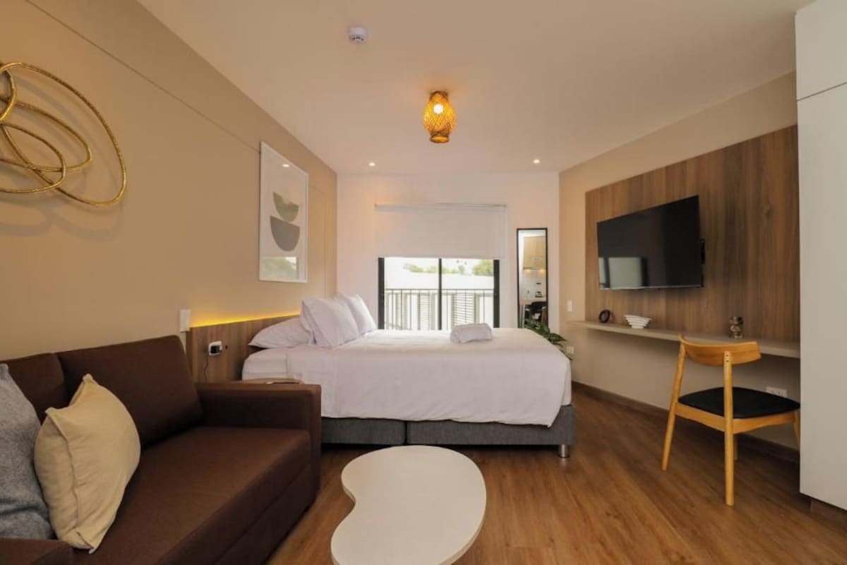 Ein modernes Hotelzimmer mit einem Bett, einem Sofa, einem Fernseher und einem kleinen Tisch.