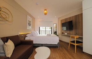Ein modernes Hotelzimmer mit einem Bett, einem Sofa, einem Fernseher und einem kleinen Tisch.