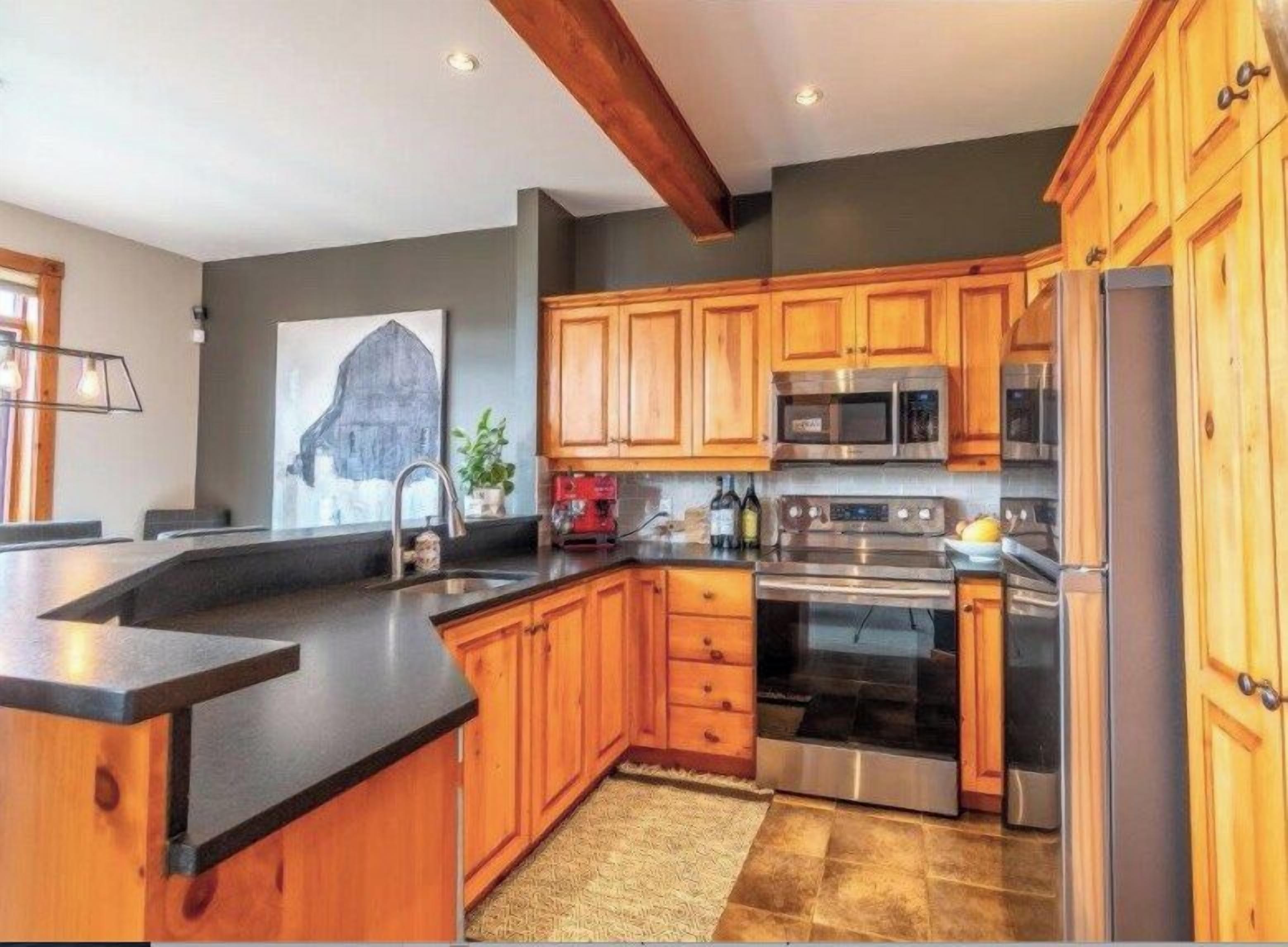 A kitchen with wooden cabinets, a stainless steel refrigerator, and a built-in oven.