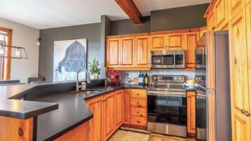 A kitchen with wooden cabinets, a stainless steel refrigerator, and a built-in oven.