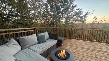 An outdoor deck with a sofa and a round table with a fire pit.