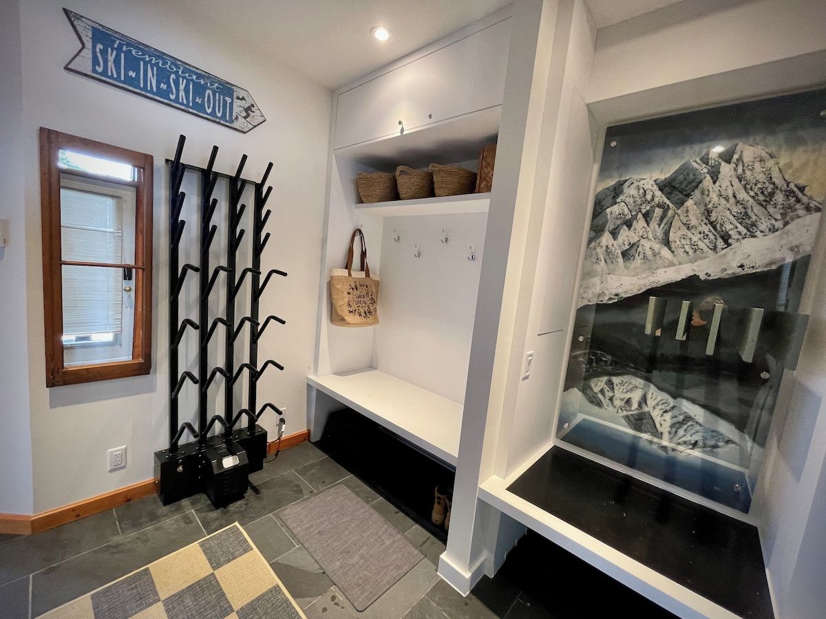 A ski-themed room with a coat rack, storage shelves, and a glass display case.