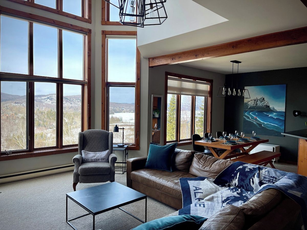 A spacious living room with large windows, a dining area, and a cozy seating arrangement.