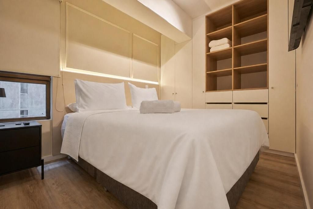 Habitación de hotel con una cama grande, armario empotrado y televisor de pantalla plana.