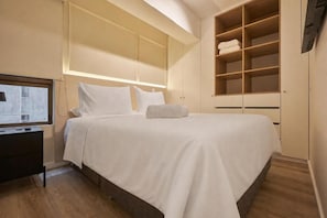 A hotel room with a large bed, built-in wardrobe, and a flat-screen TV. - Aliaga Suites With Rooftop Pool In Magdalena (Magdalena del Mar)