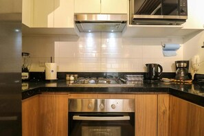 Eine kleine Küche mit einem Edelstahlbackofen, einer Mikrowelle und einer Kaffeemaschine.