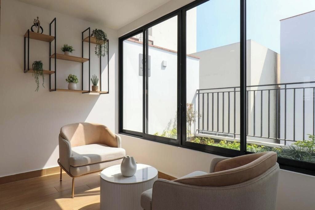Una sala de estar moderna con un sofá, una mesa de centro y un ventanal con vistas al exterior.