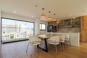 A modern kitchen with a central island, white chairs, and a large window overlooking a cityscape. - Designer 2Br Perfect View Near Costa Verde By Geko (Miraflores)