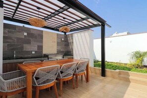 An outdoor kitchen with a wooden table and chairs, a pergola, and a view of the sky. - Designer 2Br Perfect View Near Costa Verde By Geko (Miraflores)