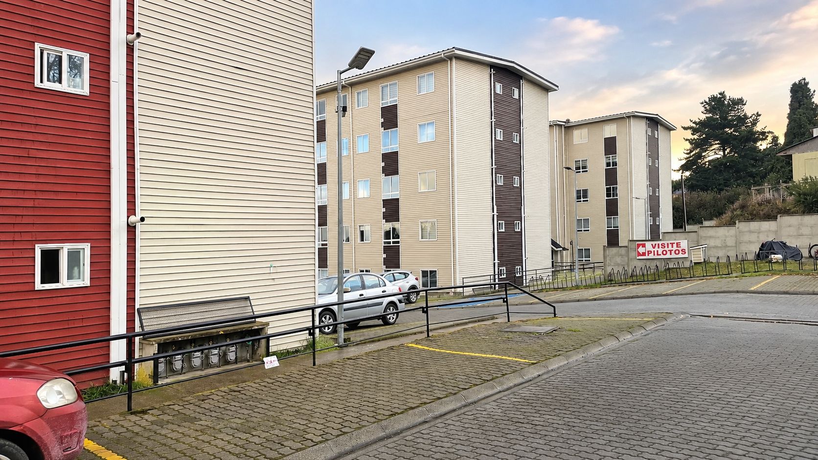 Un immeuble résidentiel à plusieurs étages avec un espace de stationnement à l’avant.