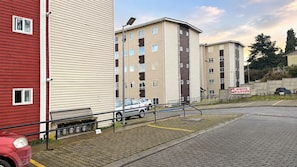 A multi-story residential building with a parking area in front.