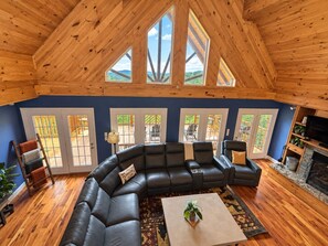 A spacious living room with a large sectional sofa, a fireplace, and large windows. - Higher Ground; Hatley Pointe ski and mtn biking (Mars Hill)