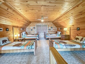 Una baita con due letti in legno, una ventola a soffitto e un pavimento rivestito di moquette.