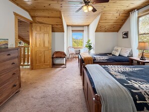 A bedroom with a wooden ceiling, a bed with patterned bedding, a dresser, and a window with a view. - Dreaming Tree Cabin; bike in/out, resort amenities (Mars Hill)