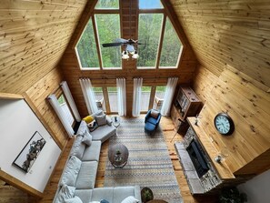 A high-ceilinged wooden interior with a sofa, armchairs, a coffee table, and a fireplace. - Dreaming Tree Cabin; bike in/out, resort amenities (Mars Hill)