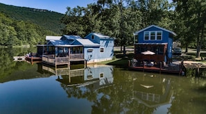 A lakeside cabin complex with docked boats, a covered deck, and a view of the surrounding forest. - The Lucky Lure is a beautiful two-bedroom cabin overlooking Johnson's Lake. (Rising Fawn)