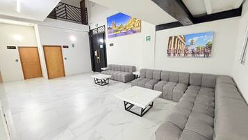 Un amplio vestíbulo con un sofá modular, una mesa de centro y una escalera.