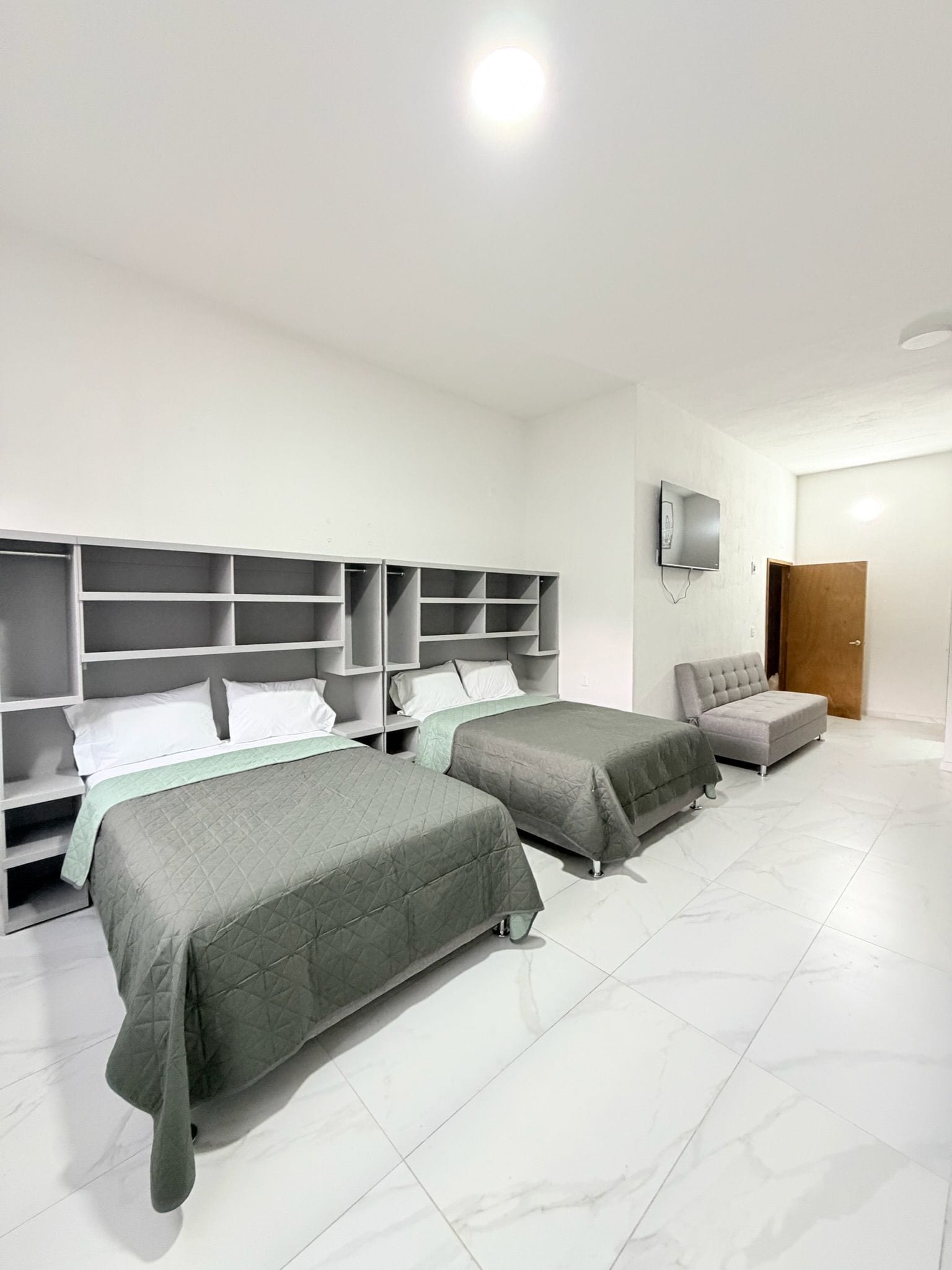 Habitación de hotel con dos camas, un armario, un televisor y una puerta.