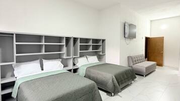 Habitación de hotel con dos camas, un armario, un televisor y una puerta.