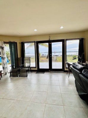 Amplia sala de estar con un gran ventanal corredero que da a un patio con vista a una masa de agua.