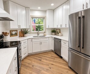 A modern kitchen with white cabinets, stainless steel appliances, and a wooden floor. - Extended Stays Welcome. Near I-75. Central between Atlanta & Chattanooga (Calhoun)