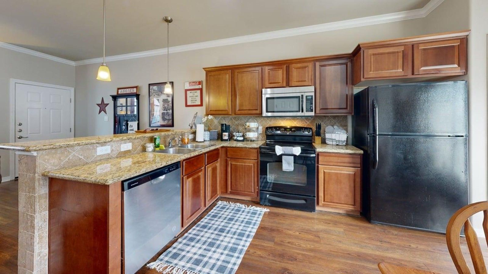 A kitchen with wooden cabinets, a black refrigerator, a microwave, a stove, and a dishwasher.
