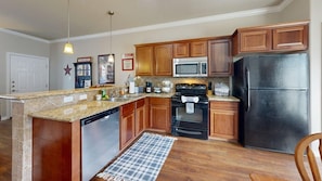 A kitchen with wooden cabinets, a black refrigerator, a microwave, a stove, and a dishwasher.