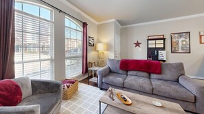 A living room with a sofa, armchair, and a coffee table. There is a lamp, a star decoration, and a framed picture on the wall.