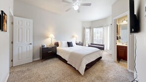 A bedroom with a bed, bedside tables, a ceiling fan, and a window with curtains.