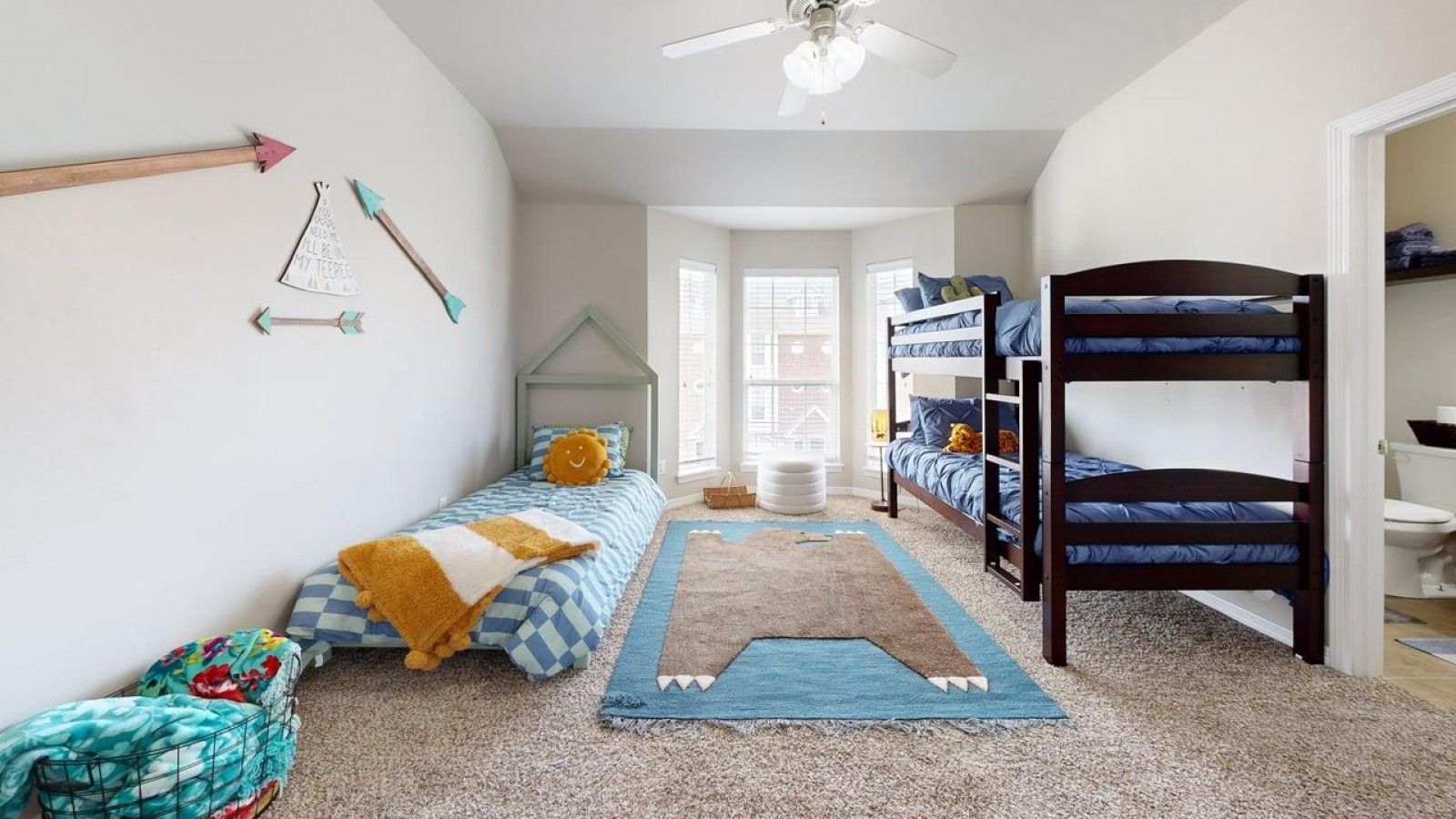 Une chambre avec des lits superposés, un ventilateur de plafond et un tapis.