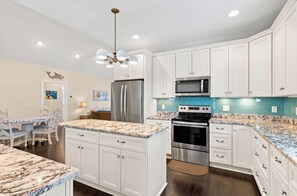 A kitchen with white cabinets, a stainless steel refrigerator, a microwave, and a stove. - Private Saltwater Pool within Walking Distance to the Beach Oak Island NC (Oak Island)