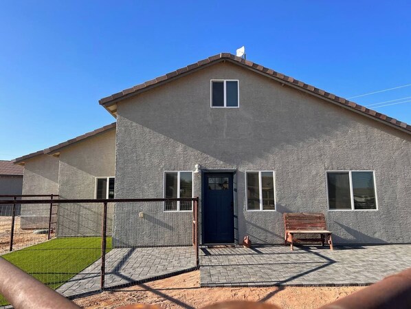 A two-story building with a flat roof, a dark blue door, and a small porch area with a bench. - Country-chic private guesthouse with laundry. (Queen Creek)