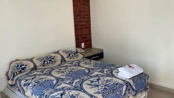 Un dormitorio con una cama, una pared de ladrillo y una lámpara.