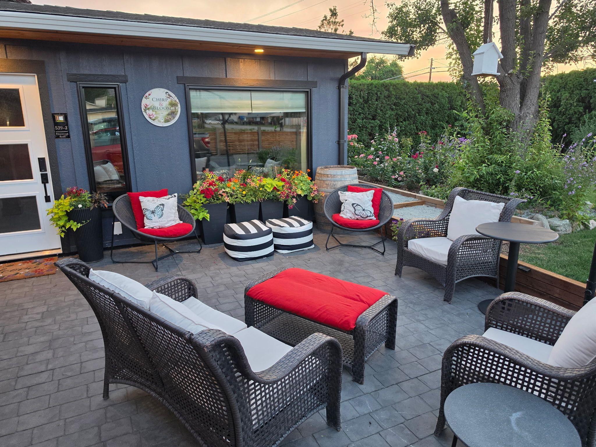 An outdoor patio with wicker furniture, a small table, and a flower planter.