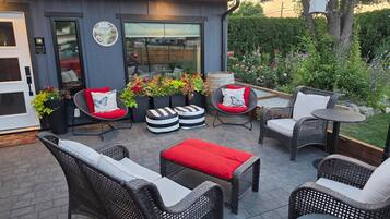 An outdoor patio with wicker furniture, a small table, and a flower planter.