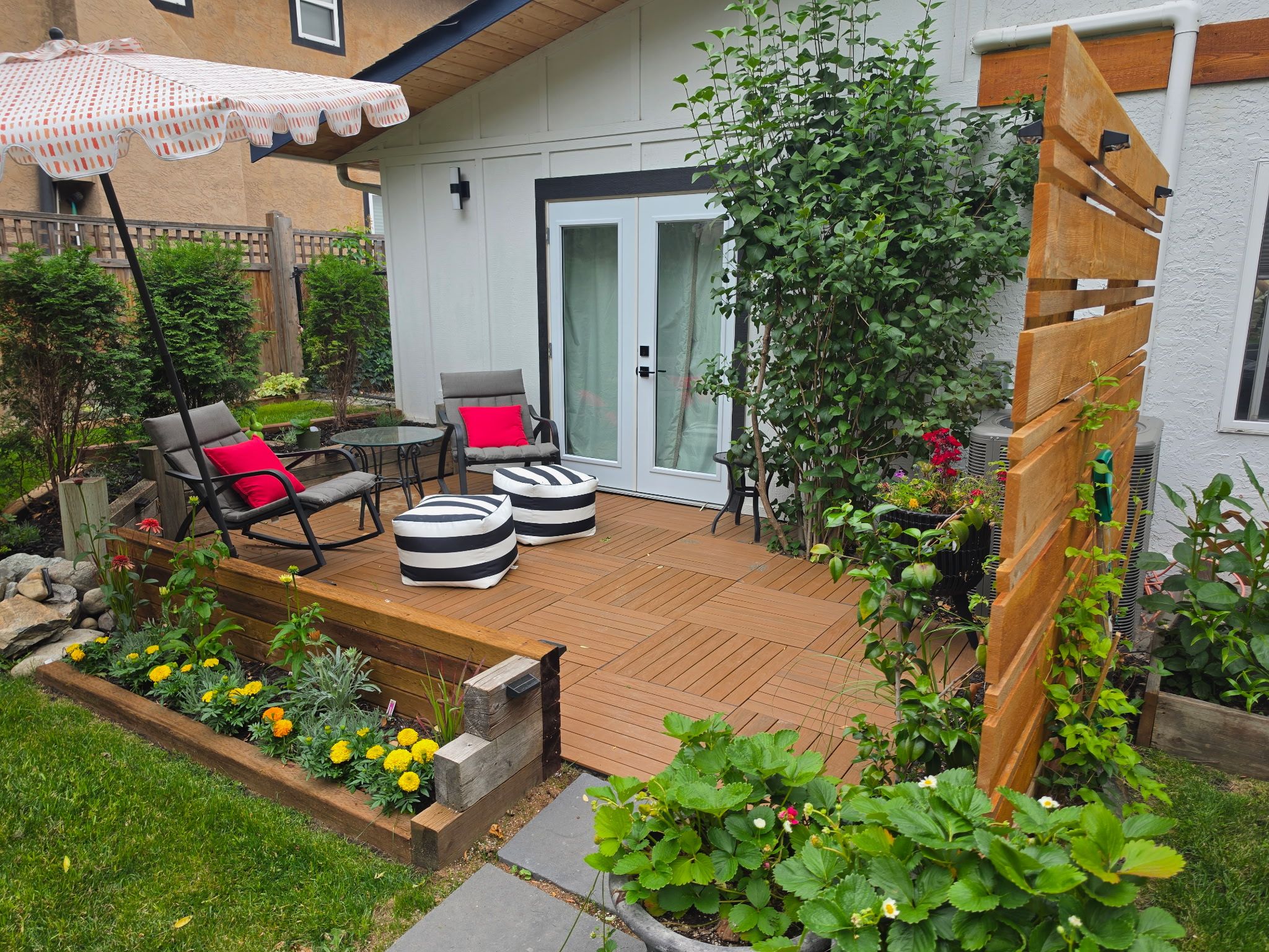 A patio with outdoor furniture, a wooden deck, and a garden with various plants and flowers.