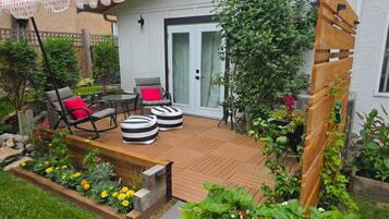 A patio with outdoor furniture, a wooden deck, and a garden with various plants and flowers.