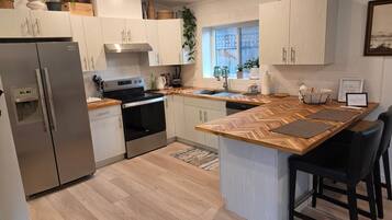 Een moderne keuken met een ingebouwde oven, een roestvrijstalen koelkast en een houten kookeiland met barkrukken.