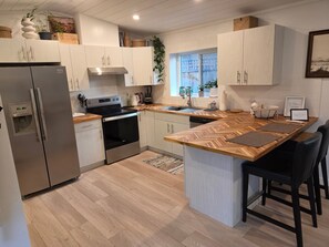 Eine moderne Küche mit Einbauofen, Edelstahlkühlschrank und einer Holzinsel mit Barhocker.