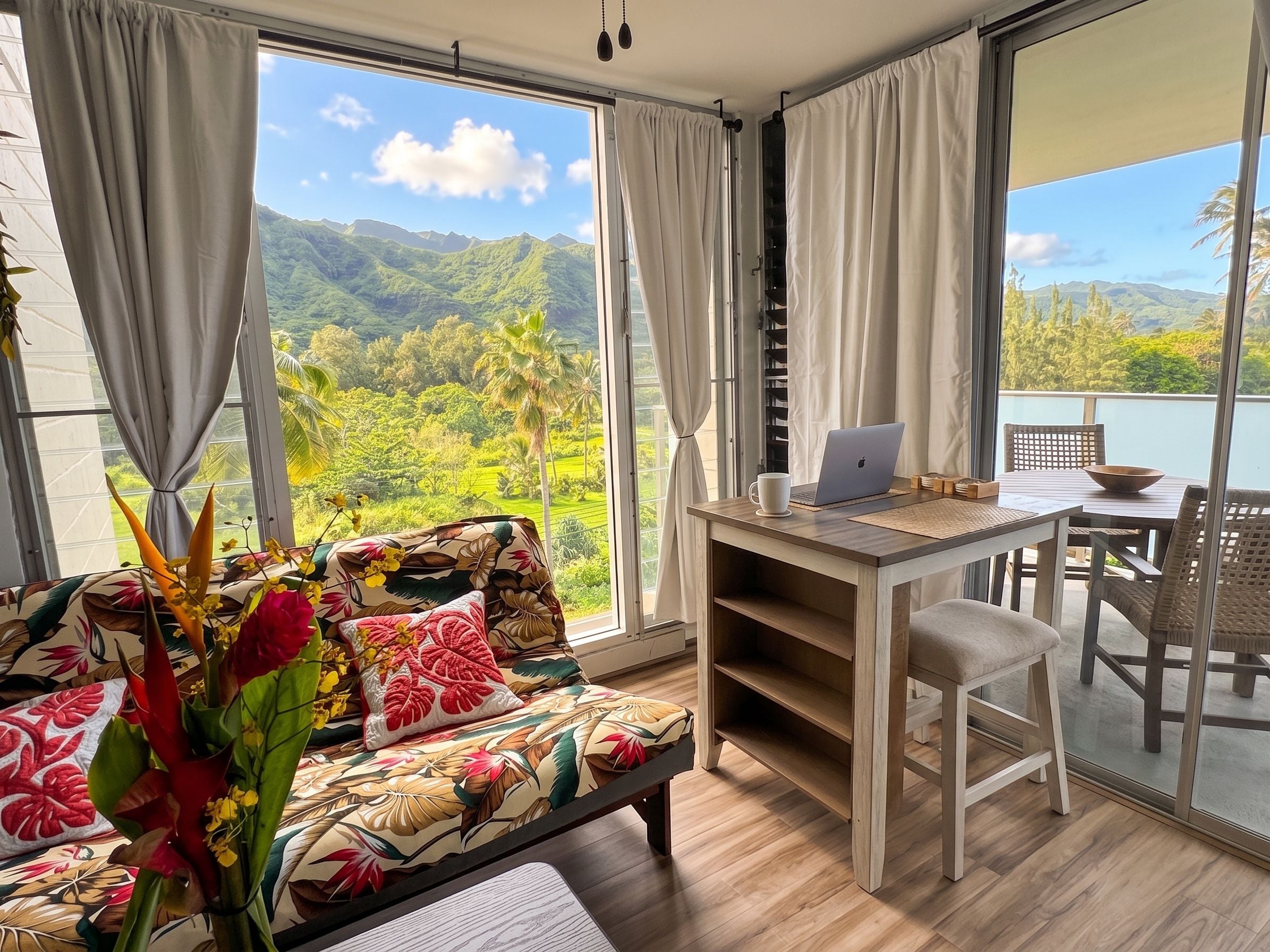 A room with a sofa, a table, and a laptop, overlooking a scenic landscape.