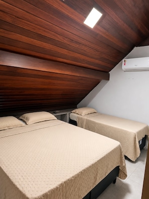 Une chambre avec deux lits, un ventilateur de plafond et un appareil de climatisation.