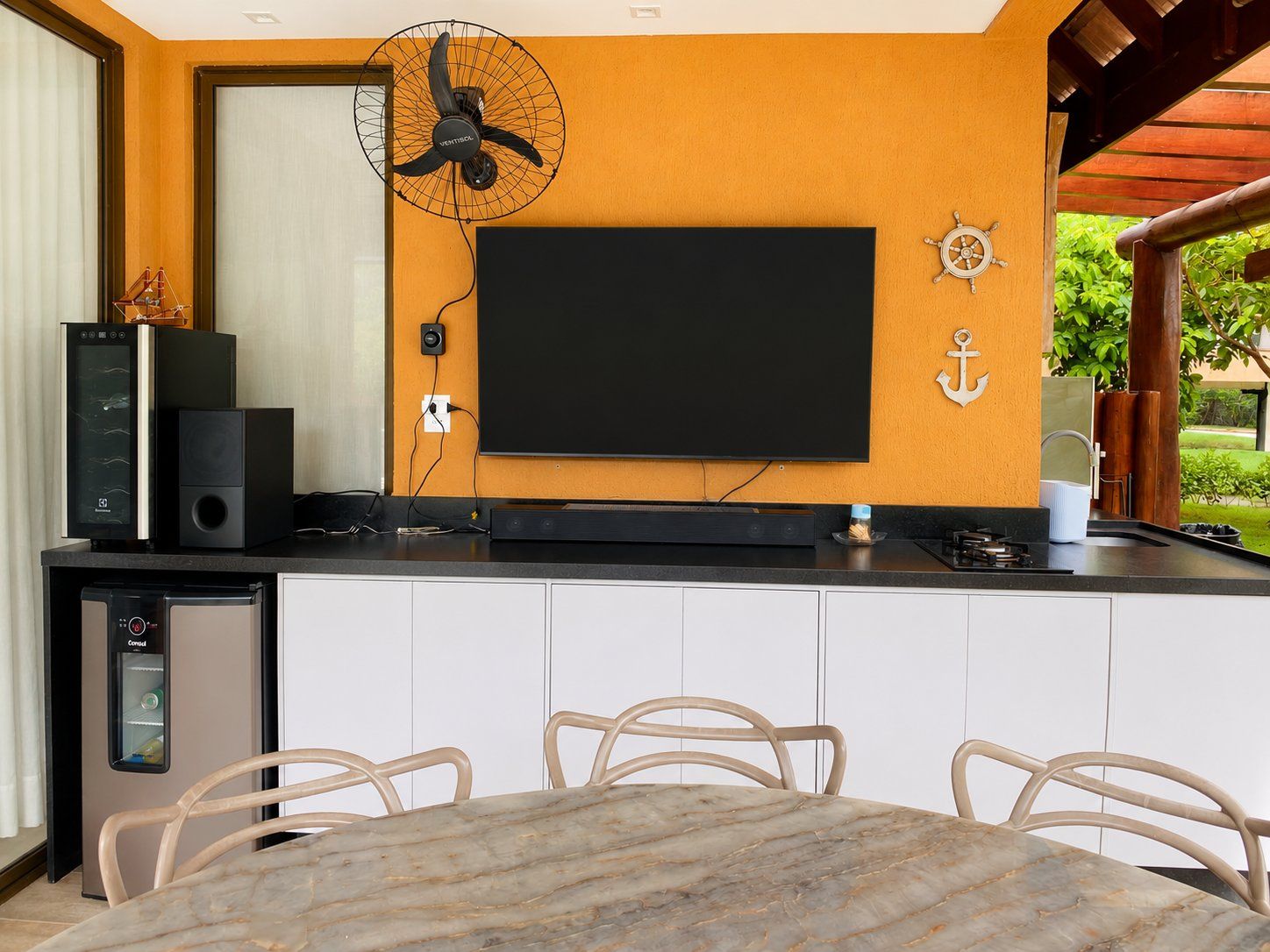 Une cuisine moderne équipée d’un téléviseur à écran plat, d’un système audio intégré et d’un réfrigérateur compact.
