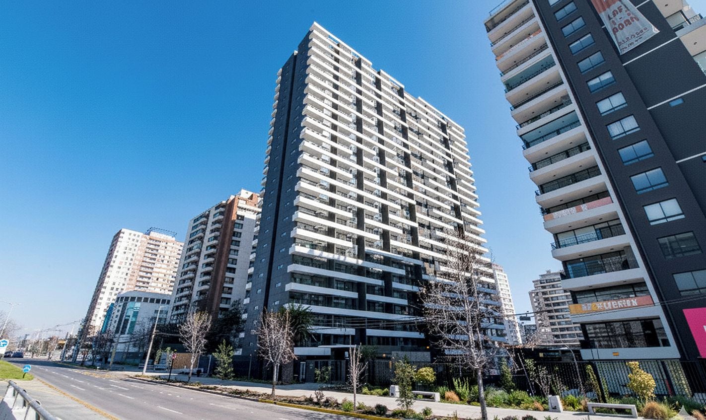 A modern high-rise building with multiple balconies and a clear sky.