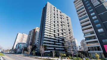 A modern high-rise building with multiple balconies and a clear sky.